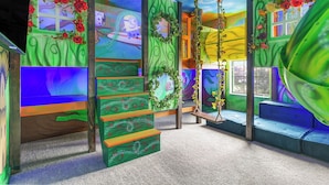 Una habitación con un diseño original y lleno de color, con una paleta verde y azul, una escalera y un ventanal con vistas al cielo.