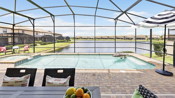 Un espace extérieur abrité comprenant une piscine, des chaises longues et une table avec des fruits.