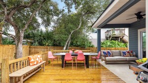 Une terrasse extérieure avec une plateforme en bois, une table ronde entourée de chaises, un banc et un canapé.