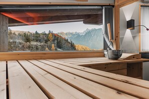 A wooden table with a view of a mountainous landscape through a window. - See the Holiday Home with Lake View, Private Terrace and Wi-Fi (Oetz)
