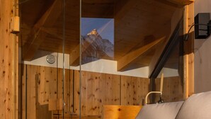 A wooden interior with a bed, a wooden bench, and a view of a mountain through a glass wall. - See the Holiday Home with Lake View, Private Terrace and Wi-Fi (Oetz)