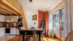 A modern kitchen with wooden beams, a dining area with a table and chairs, and a large window with curtains.