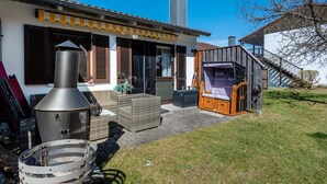 A house with a patio, a grill, wicker furniture, and a wooden deck.