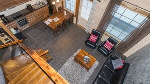 Eine moderne Küche mit Holzausstattung, ein Essbereich mit Tisch und Stühlen sowie ein Wohnzimmer mit Sofa und Couchtisch.
