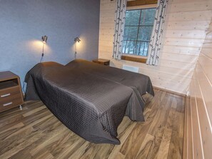 Une chambre avec deux lits, un plancher en bois, une fenêtre avec des rideaux et des lampes fixées au mur.