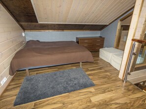 Une chambre à coucher avec un lit, une commode, un banc et une fenêtre.