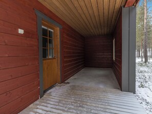 Una cabana de fusta amb un porxo cobert i una porta que dóna a l'interior.
