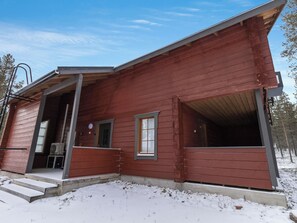 A red wooden cabin with a porch, a small window, and a door. - Unelmarakka b by Interhome (Kittilä)