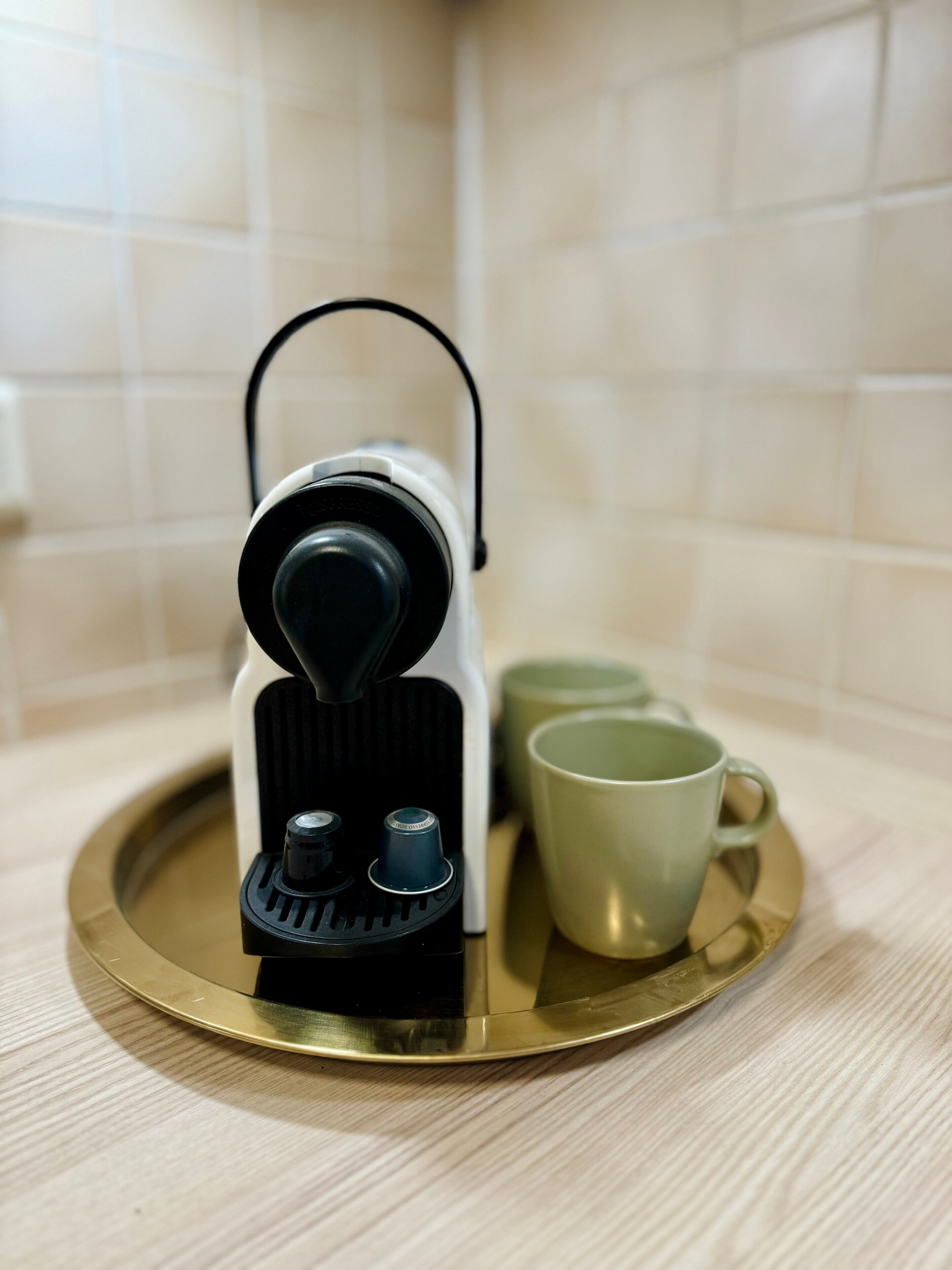 A coffee machine on a tray with two cups.