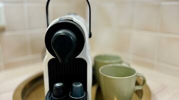 A coffee machine on a tray with two cups.