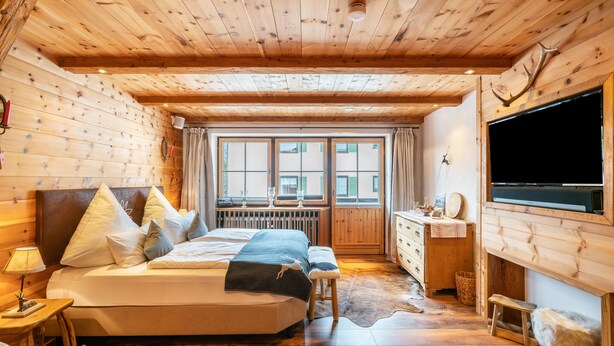 A wooden cabin bedroom with a bed, a dresser, a TV, and a window with a view. - Studio Apartment "Chalet Bergliebe Inzell mit Zirbenholz" with Mountain View & Wi-Fi (Inzell)
