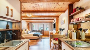 A cozy kitchen with wooden cabinets, a sink, and a dining area with a table and chairs. - Studio Apartment "Chalet Bergliebe Inzell mit Zirbenholz" with Mountain View & Wi-Fi (Inzell)
