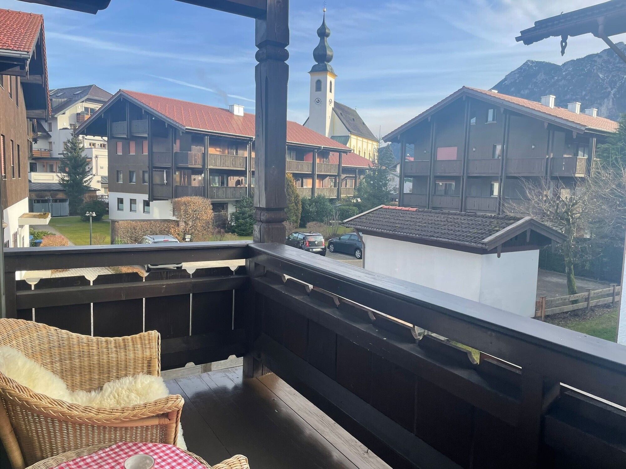 A balcony with wicker furniture, a view of traditional buildings, and a church tower.