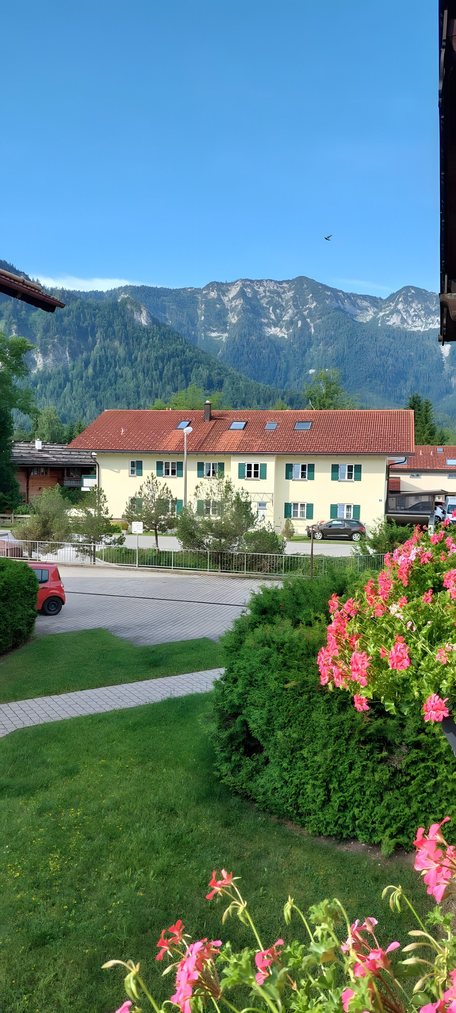A building with a red-tiled roof, a paved driveway, and a mountain backdrop.