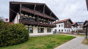 A traditional chalet-style building with a wooden balcony, a paved pathway, and a well-maintained lawn. - Studio Apartment "Chalet Bergliebe Inzell mit Zirbenholz" with Mountain View & Wi-Fi (Inzell)
