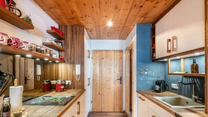 A modern kitchen with wooden cabinetry, a central island, and a built-in stove. - Studio Apartment "Chalet Bergliebe Inzell mit Zirbenholz" with Mountain View & Wi-Fi (Inzell)