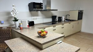 Et moderne køkken med en granitbordplade, en mikrobølgeovn, en kaffemaskine og en skål med frugt.