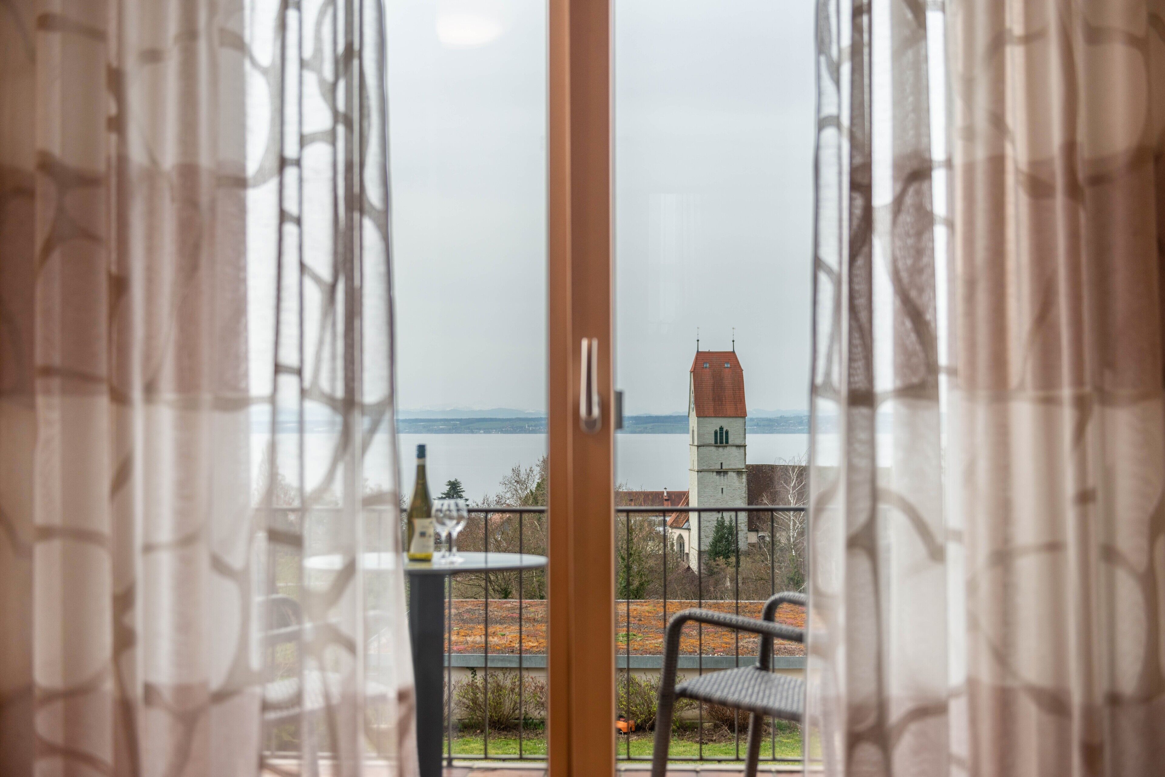 Blick vom Balkon mit Tisch, Stühlen, einer Weinflasche und einer entfernten Aussicht auf einen Turm und die Landschaft.