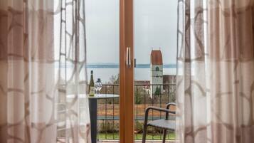 Blick vom Balkon mit Tisch, Stühlen, einer Weinflasche und einer entfernten Aussicht auf einen Turm und die Landschaft.