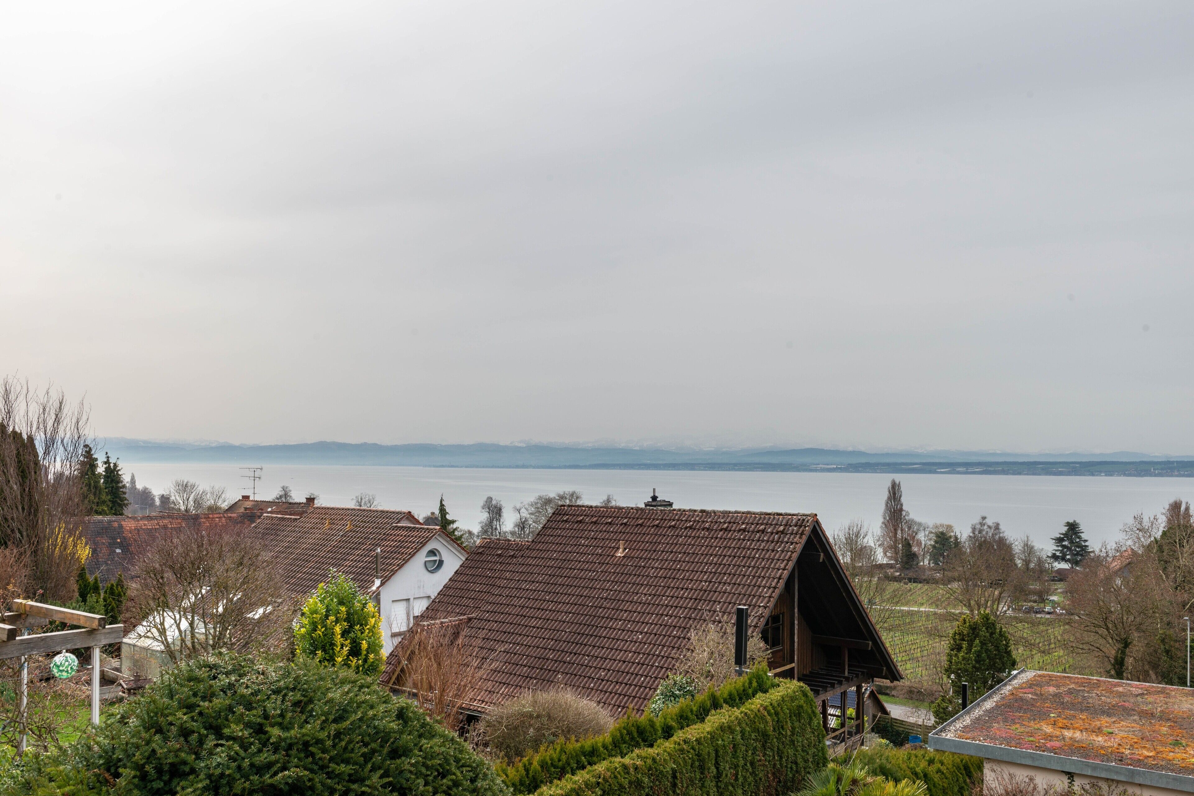 Zona residenziale con case, vista aperta su un lago e montagne in lontananza.