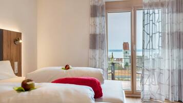 Una camera d'albergo con un letto, una finestra con tende e vista all'esterno.