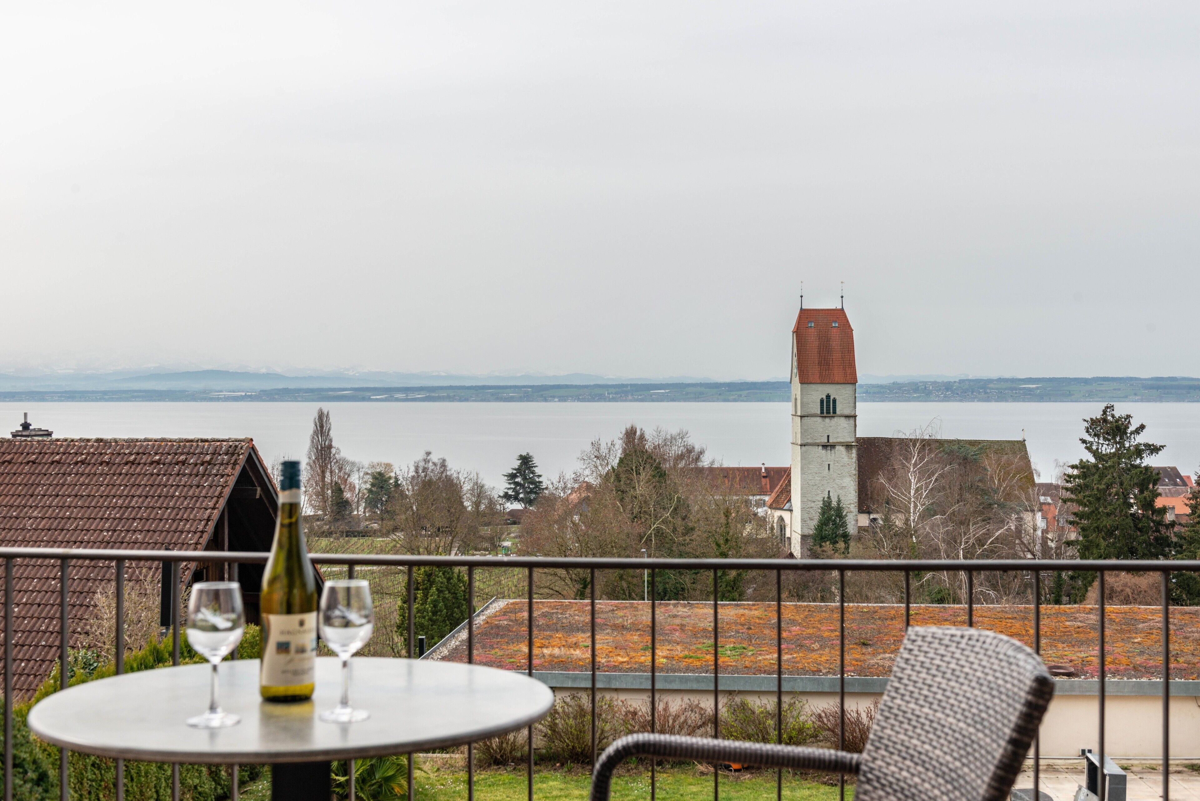 Ein Balkon mit Tisch, zwei Weingläsern und einer Weinflasche.