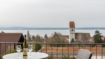Ein Balkon mit Tisch, zwei Weingläsern und einer Weinflasche.