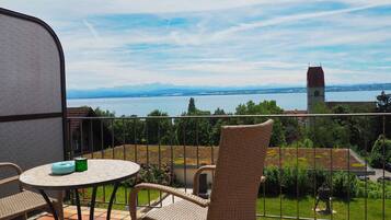 Un balcone con mobili in vimini, vista su un lago e una torre in lontananza.