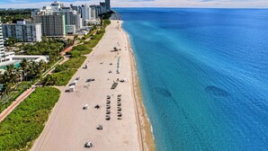 A coastal cityscape with a wide beach, high-rise buildings, and a clear blue sea. - Luxury Beach Condo with Exclusive Resort Amenities 1016 (Miami Beach)