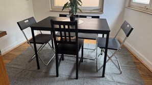 A dining area with a table and four chairs, a potted plant, and a window with blinds. - Pfullingen 1 – Accommodation for Workers, Worker House Single Rooms, Wi-Fi (Pfullingen)
