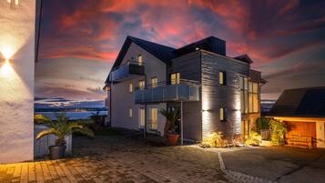 Una moderna casa a due piani con un balcone, un vialetto lastricato e vista sul mare.