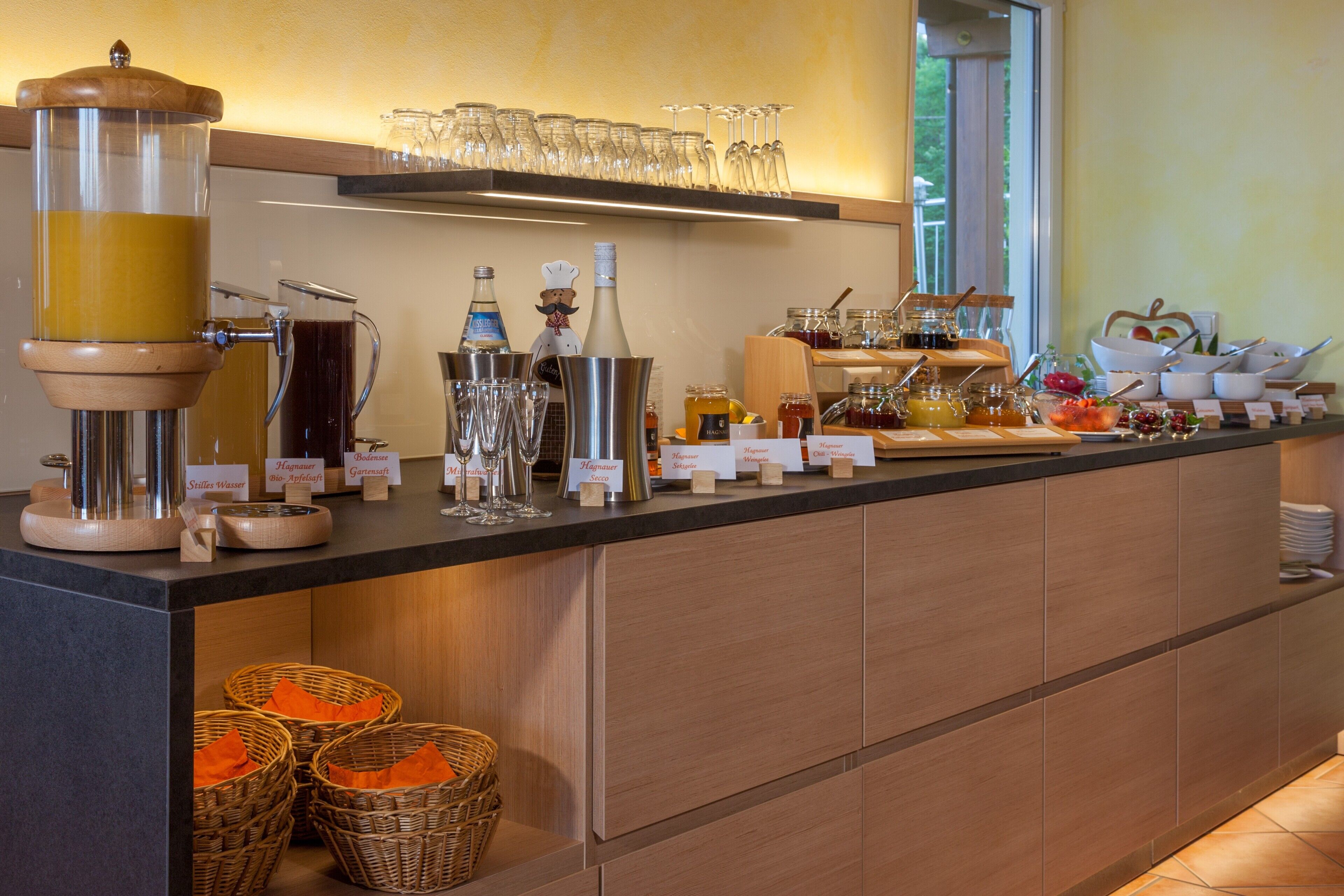 Un'area buffet con diversi distributori di cibo e bevande, bicchieri e cestini.