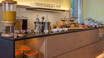 Un'area buffet con diversi distributori di cibo e bevande, bicchieri e cestini.