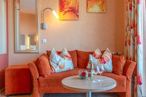 A cozy living room with a sofa, a round coffee table, and a bottle of wine. - Comfort Room with Side Lake View, Balcony and Wi-Fi (Hagnau am Bodensee)