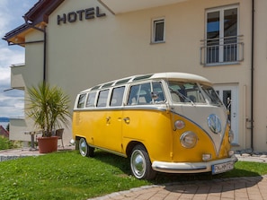 A yellow and white vintage VW camper van parked in front of a building with a sign that reads 'HOTEL'. - Comfort Room with Side Lake View, Balcony and Wi-Fi (Hagnau am Bodensee)
