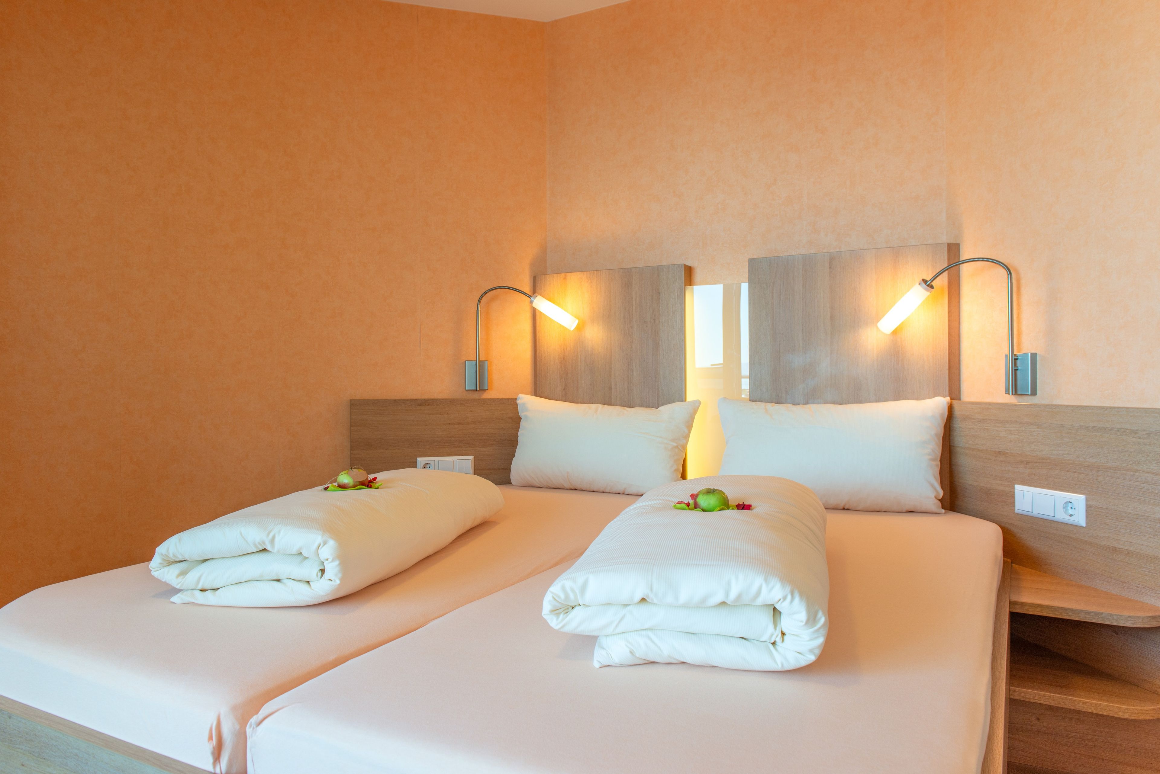 Ein Hotelzimmer mit einem Doppelbett, zwei Nachttischen und Wandlampen.