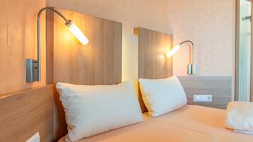 Ein Hotelzimmer mit einem hölzernen Kopfteil, zwei Nachttischlampen und einem Bett mit weißer Bettwäsche.