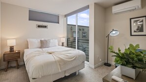 A bedroom with a large bed, bedside lamps, a nightstand, a potted plant, and a view of the outside. - Rooftop Vibes!  Greenlake UW Near Down Town (Seattle)