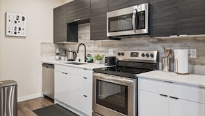 A modern kitchen with white cabinets, stainless steel appliances, and a microwave above the stove. - Rooftop Vibes!  Greenlake UW Near Down Town (Seattle)