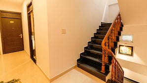 A staircase with wooden railings leading to an upper floor, a door on the left, and a framed picture on the wall. - An's House  (Xuan Huong - Da Lat)