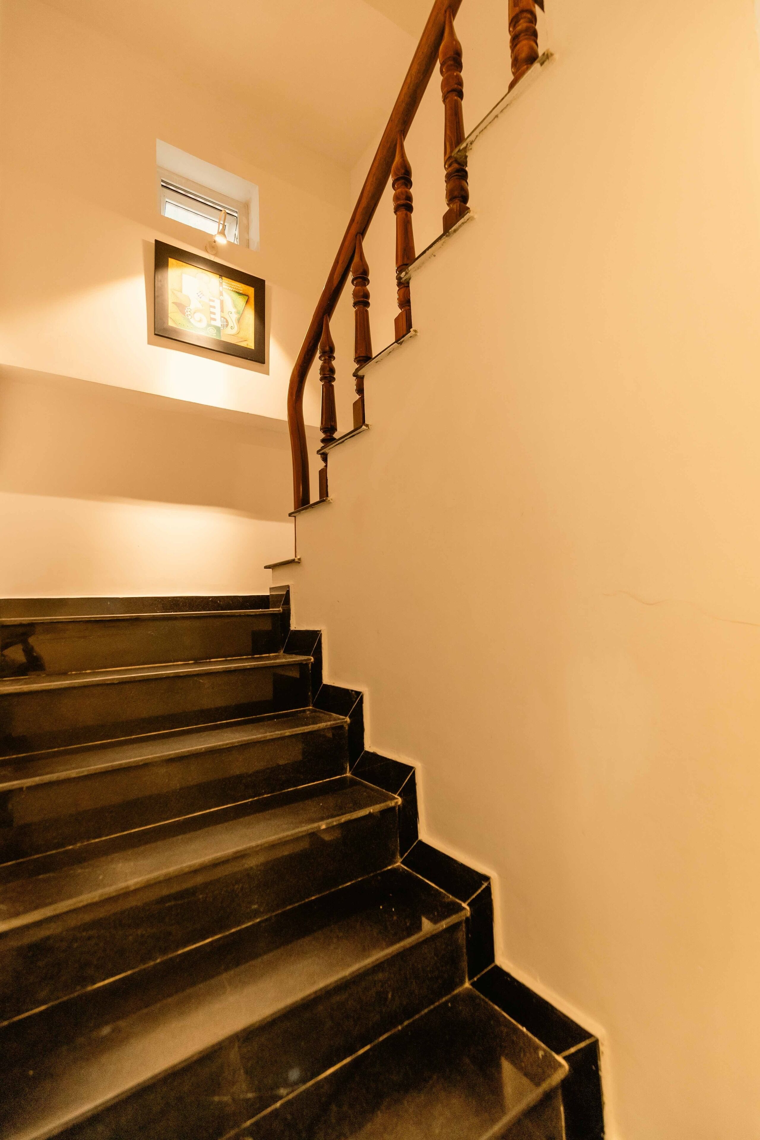 A staircase with wooden handrails and a framed picture on the wall above.
