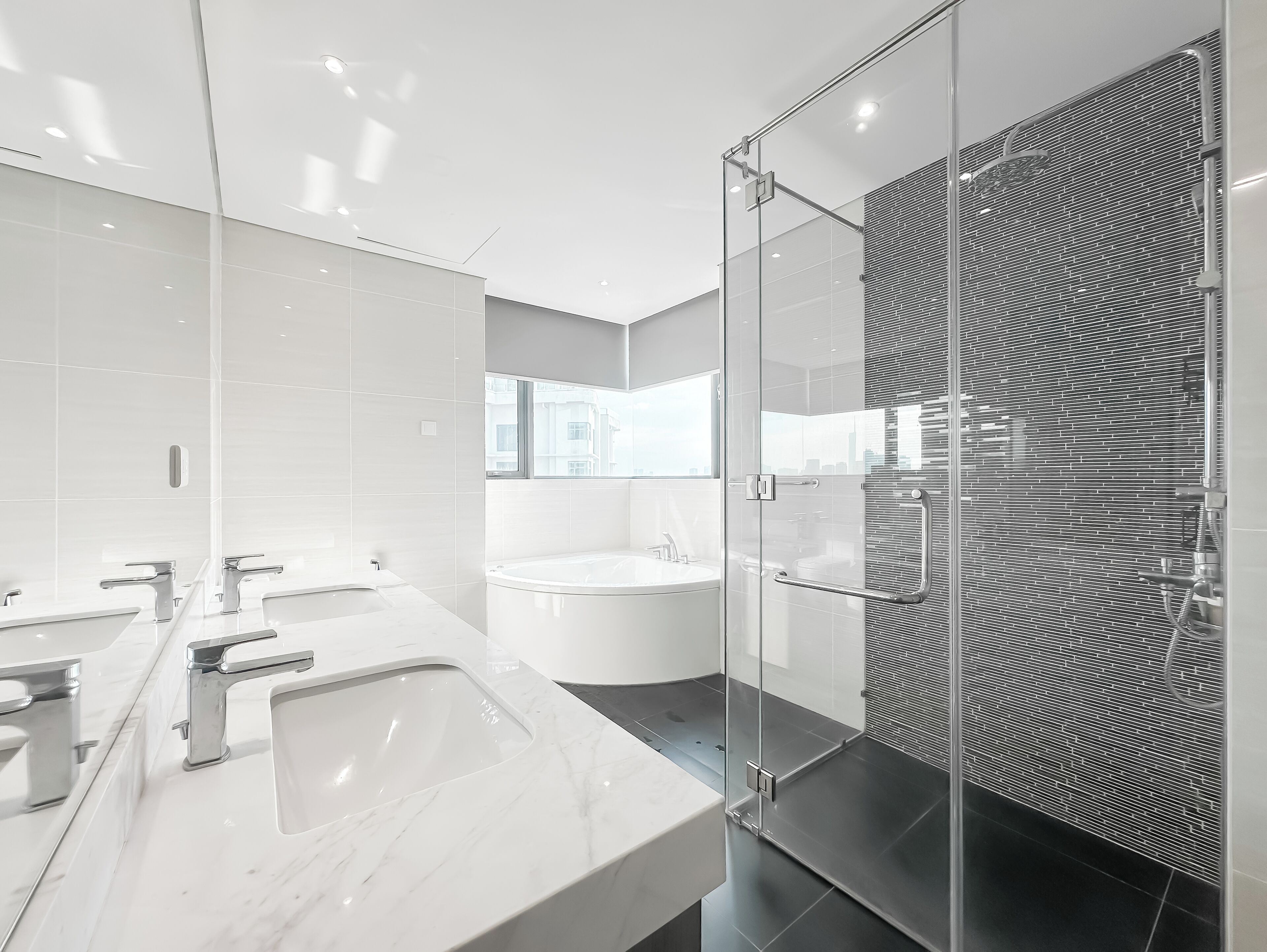A modern bathroom with a large mirror, two sinks, a bathtub, and a glass-enclosed shower area.