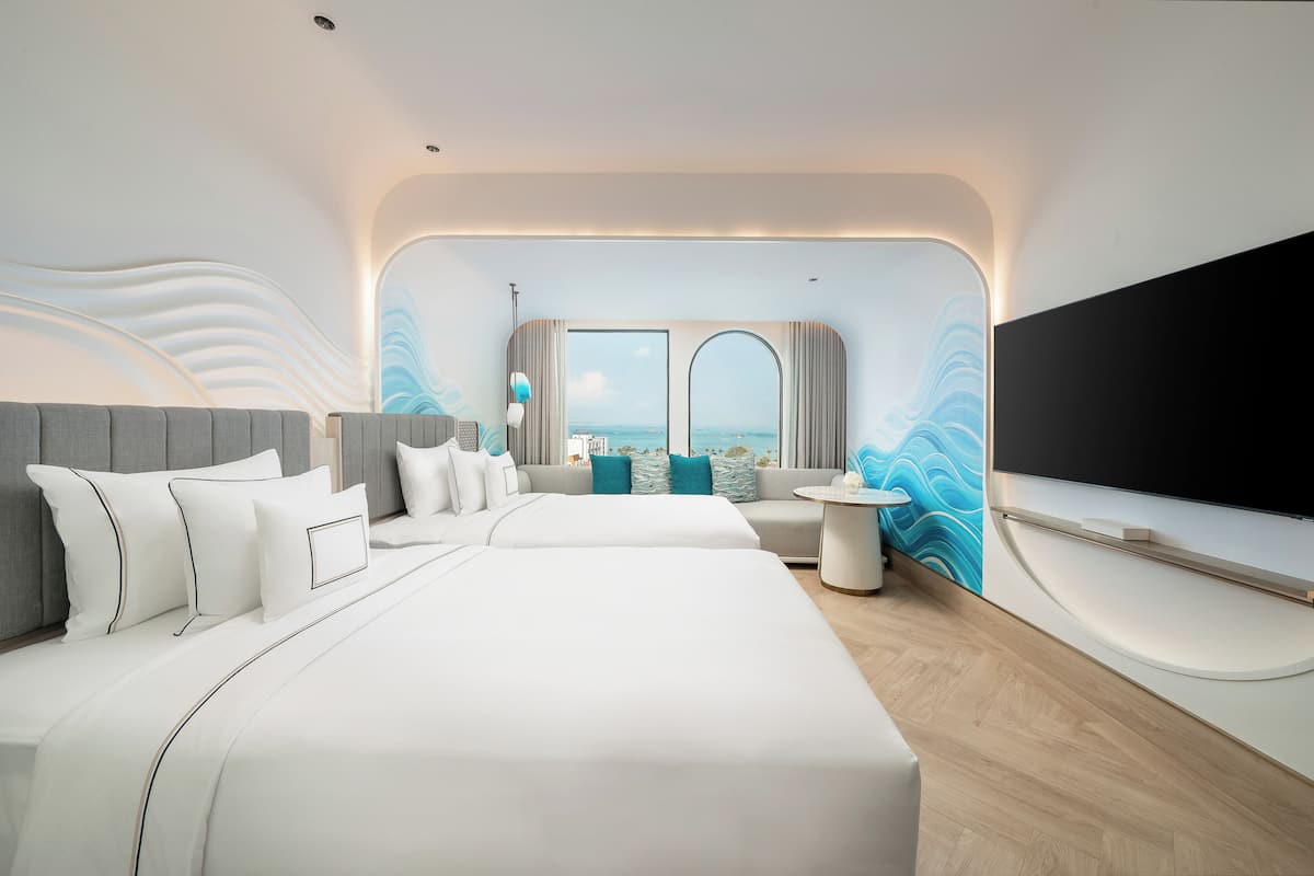 Ein modernes Hotelzimmer mit einem großen Bett, einer Couch, einem Fernseher und Meerblick.