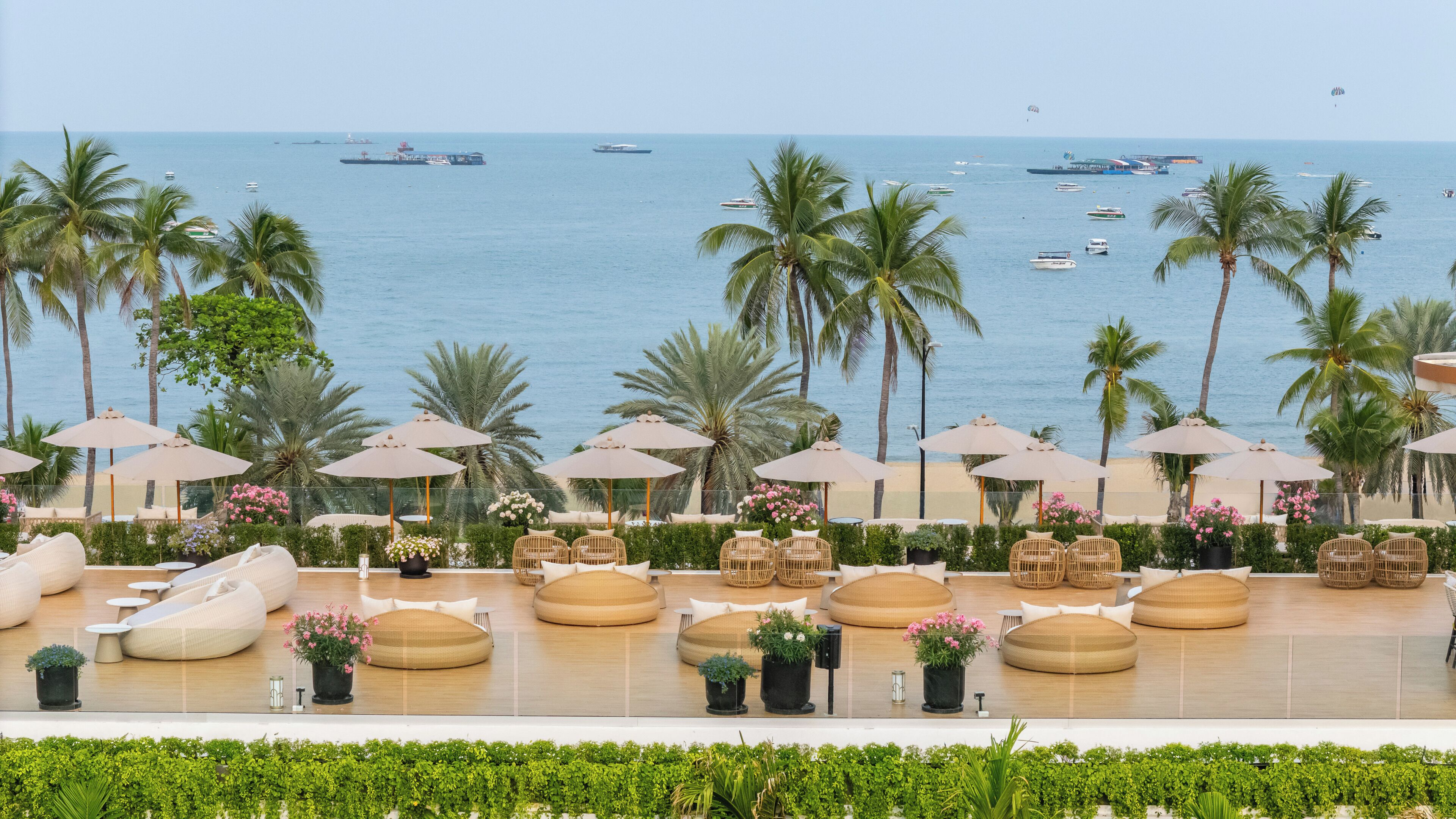 A beachfront lounge area with outdoor seating, umbrellas, and a view of the sea.