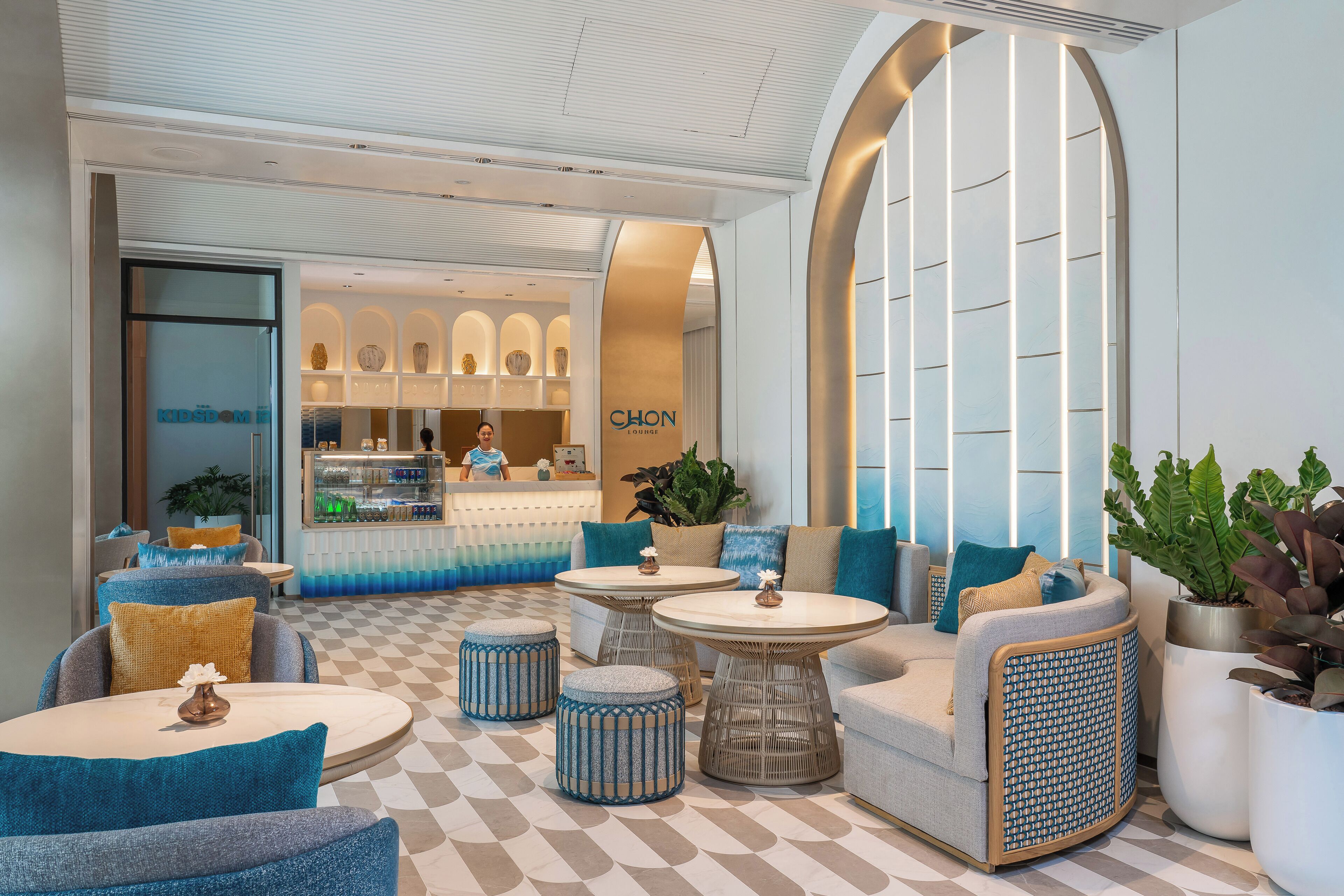 A modern lobby with seating areas, a reception desk, and a visible store named 'CHON'.