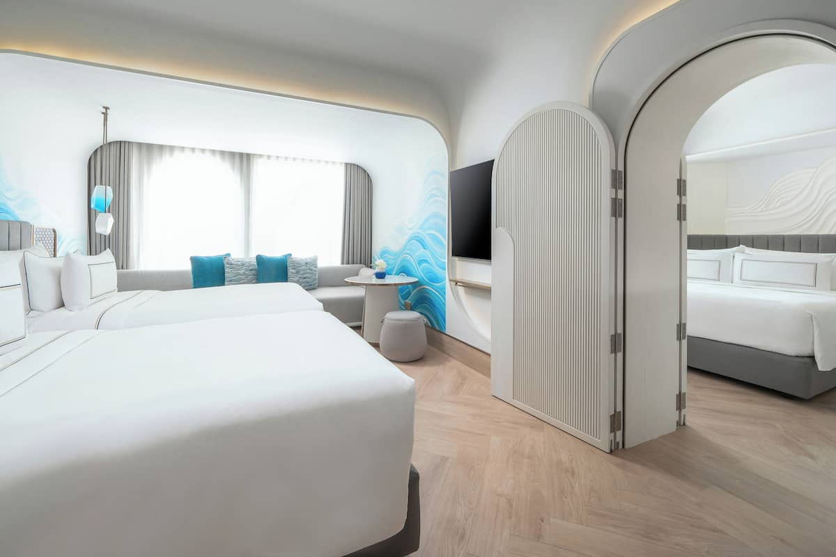 Ein modernes Hotelzimmer mit einem großen Bett, einer Sitzecke und einem Fernseher.