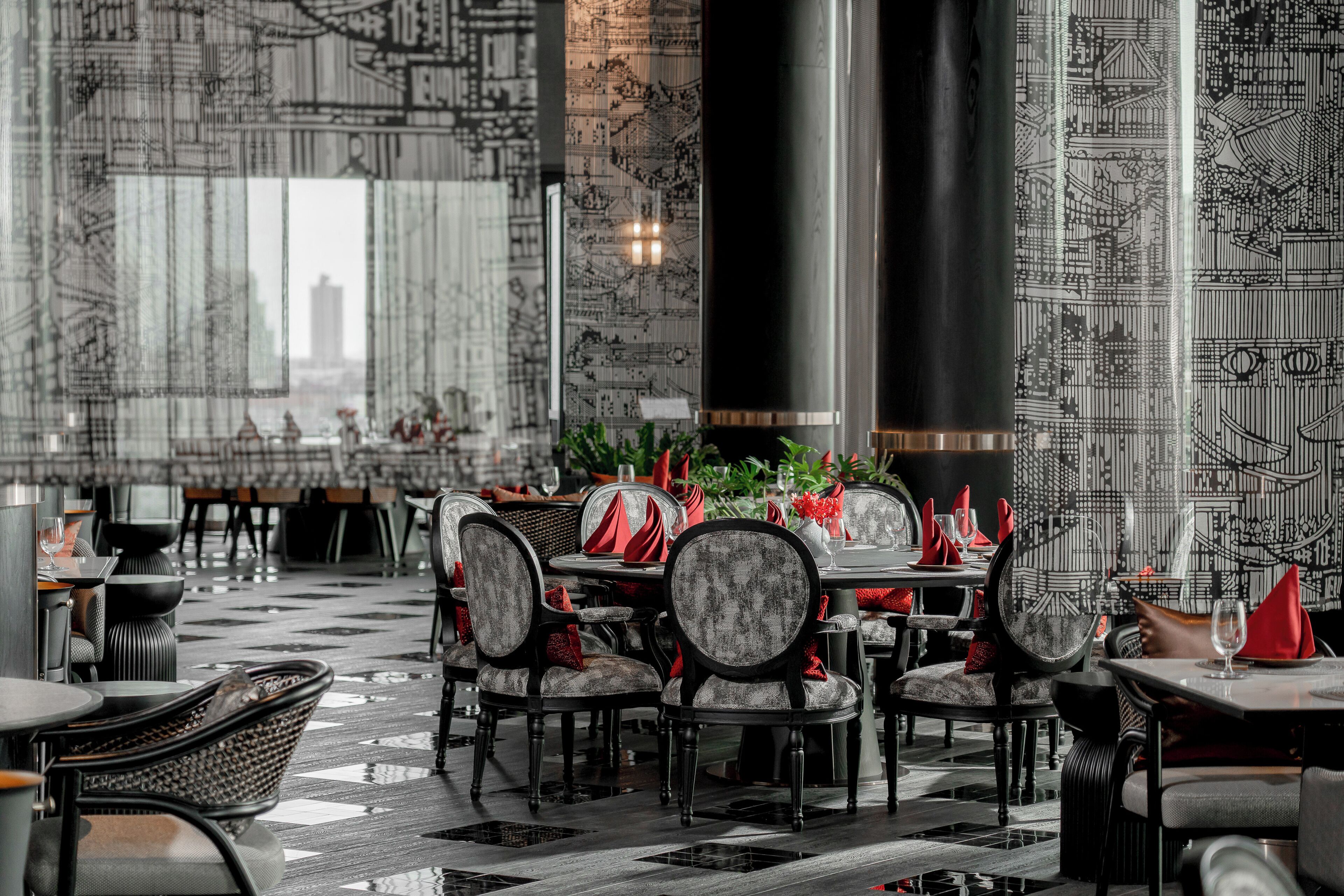 A restaurant with a checkered floor, patterned walls, and a cityscape view.