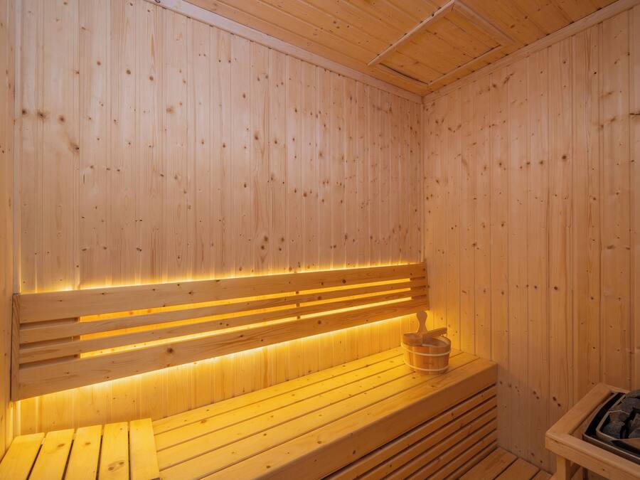 Una sauna de madera con bancos y un asiento con un cubo.