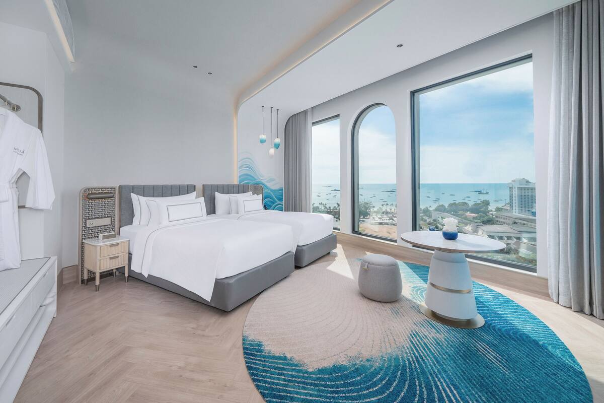 Ein modernes Hotelzimmer mit einem großen Bett, einem kleinen Tisch und Blick auf das Meer.