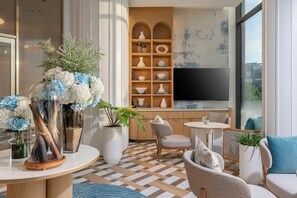 Una sala de estar moderna con un televisor grande, una estantería de madera y asientos cómodos.
